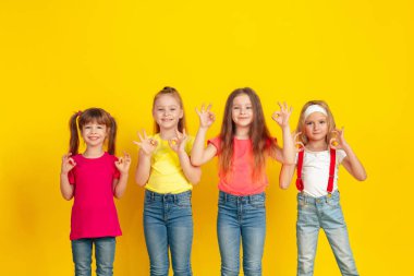 Happy children playing and having fun together on yellow studio background