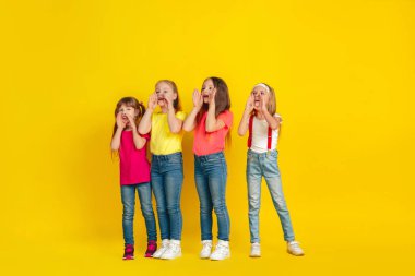 Happy children playing and having fun together on yellow studio background