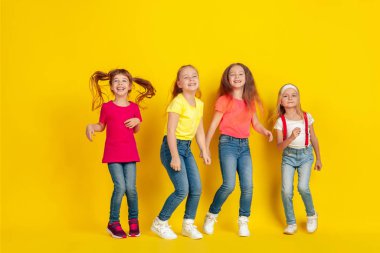 Happy children playing and having fun together on yellow studio background
