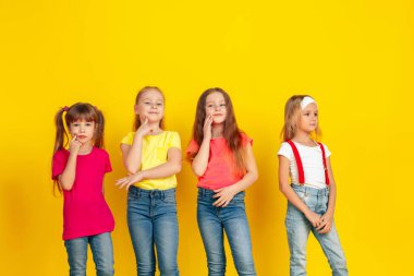 Happy children playing and having fun together on yellow studio background