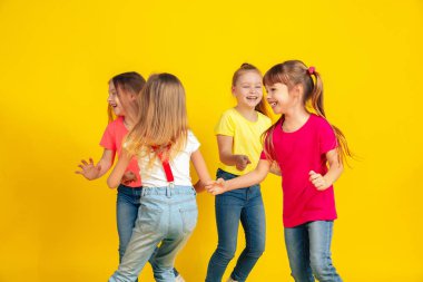 Happy children playing and having fun together on yellow studio background