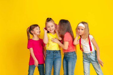 Happy children playing and having fun together on yellow studio background