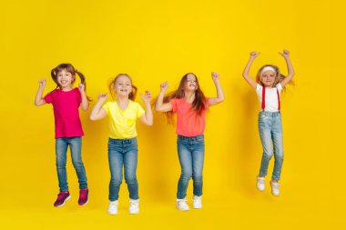 Happy children playing and having fun together on yellow studio background