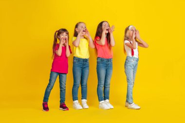 Happy children playing and having fun together on yellow studio background