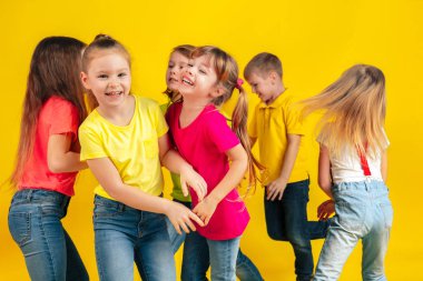 Happy children playing and having fun together on yellow studio background