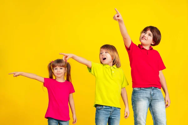 Niños felices jugando y divirtiéndose juntos en el fondo amarillo del estudio — Foto de Stock