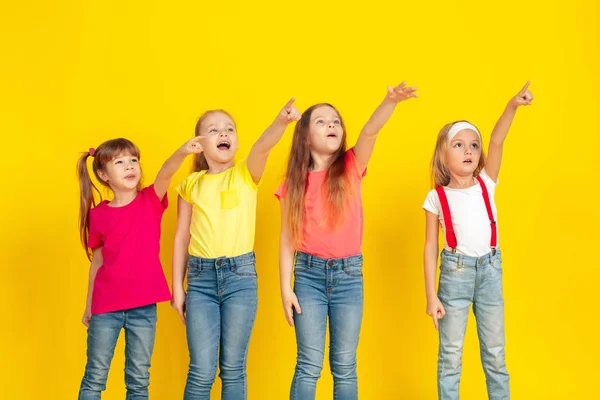 Happy children playing and having fun together on yellow studio background — ストック写真