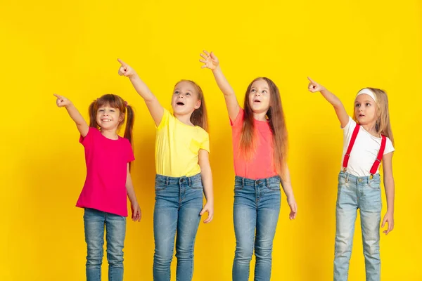 Enfants heureux jouant et s'amusant ensemble sur fond jaune studio — Photo