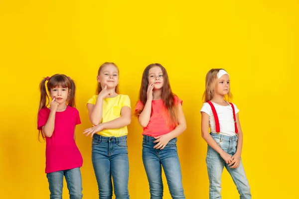 Niños felices jugando y divirtiéndose juntos en el fondo amarillo del estudio — Foto de Stock