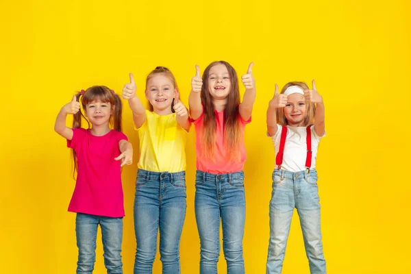 Niños felices jugando y divirtiéndose juntos en el fondo amarillo del estudio — Foto de Stock