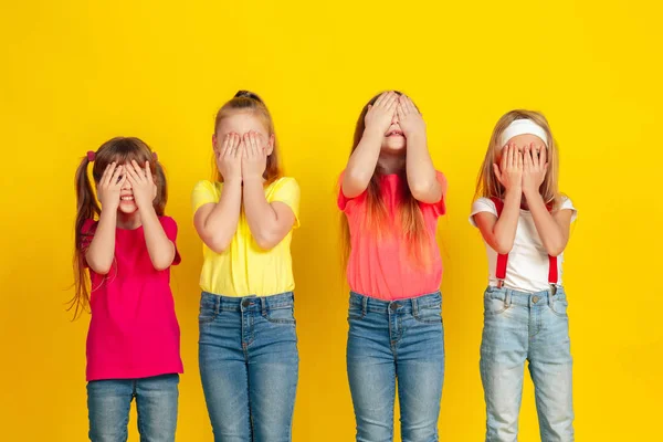 Happy children playing and having fun together on yellow studio background — ストック写真