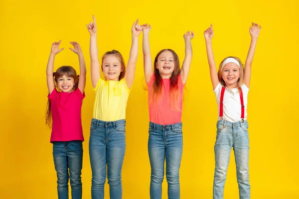 Crianças felizes brincando e se divertindo juntas no fundo do estúdio amarelo — Fotografia de Stock