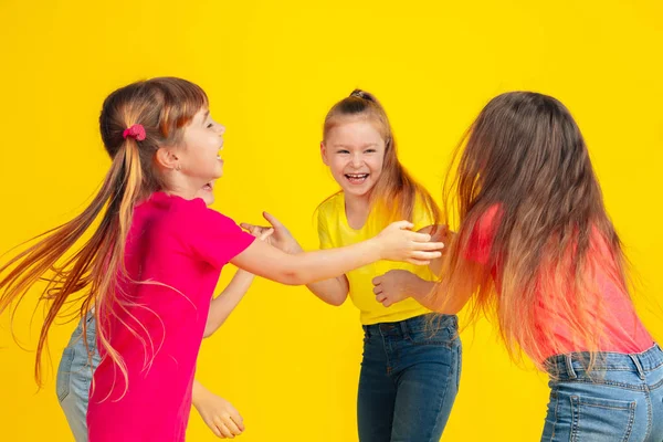 Happy children playing and having fun together on yellow studio background — Stockfoto