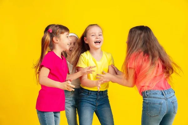 Crianças felizes brincando e se divertindo juntas no fundo do estúdio amarelo — Fotografia de Stock