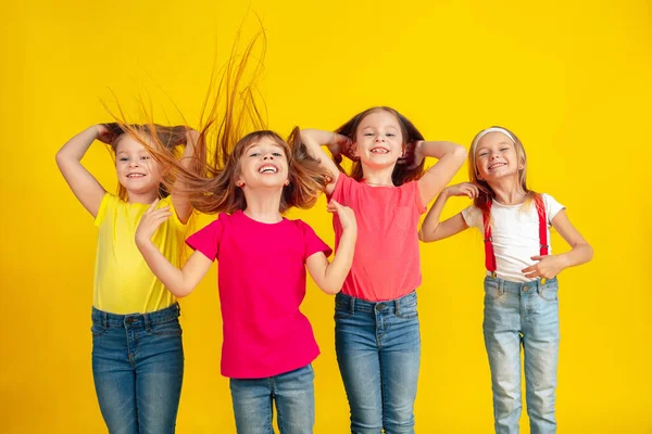 Happy children playing and having fun together on yellow studio background — Φωτογραφία Αρχείου