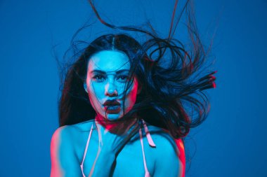 Attractive brunette model on blue studio background in neon light