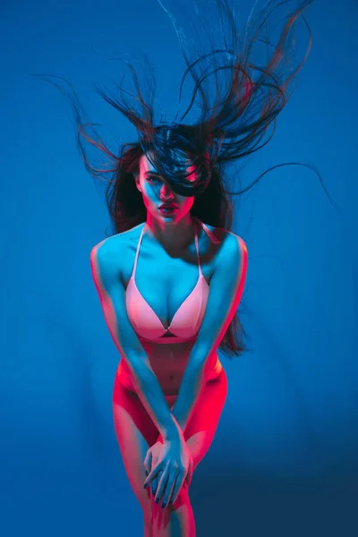 Atractiva modelo morena sobre fondo estudio azul en luz de neón — Foto de Stock