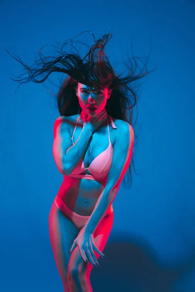 Attractive brunette model on blue studio background in neon light — ストック写真