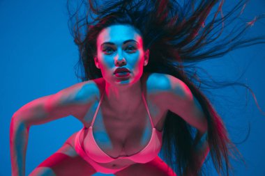 Attractive brunette model on blue studio background in neon light