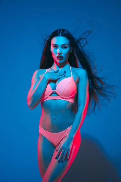 Atractiva modelo morena sobre fondo estudio azul en luz de neón — Foto de Stock