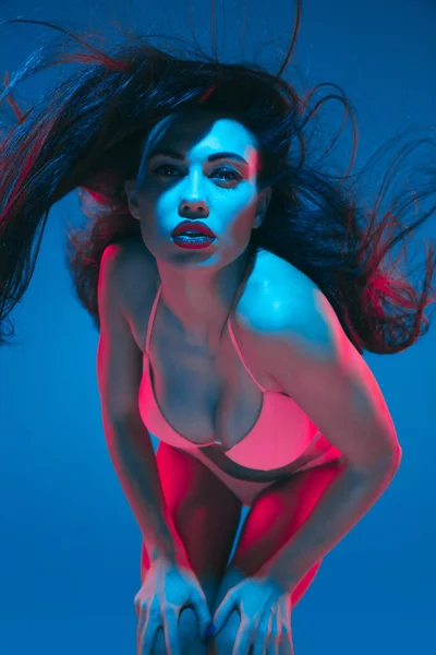 Attractive brunette model on blue studio background in neon light — ストック写真