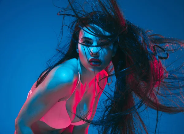 Attractive brunette model on blue studio background in neon light — Stock Photo, Image