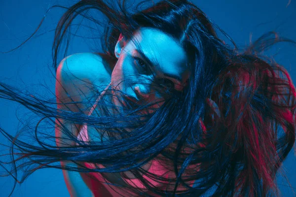Modelo morena atraente no fundo do estúdio azul em luz de néon — Fotografia de Stock