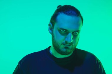 Yeşil arka planda renkli neon ışığı olan bir adamın portresi - siber punk konsepti