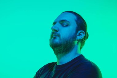 Yeşil arka planda renkli neon ışığı olan bir adamın portresi - siber punk konsepti