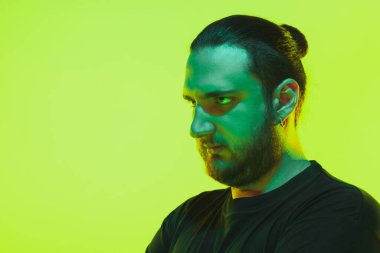 Yeşil arka planda renkli neon ışığı olan bir adamın portresi - siber punk konsepti