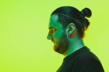 Yeşil arka planda renkli neon ışığı olan bir adamın portresi - siber punk konsepti