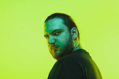Yeşil arka planda renkli neon ışığı olan bir adamın portresi - siber punk konsepti