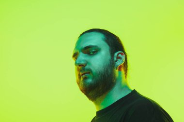 Yeşil arka planda renkli neon ışığı olan bir adamın portresi - siber punk konsepti