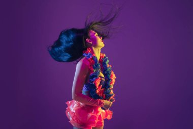 Attractive hawaiian brunette model on purple studio background in neon light