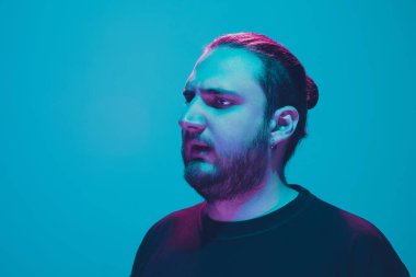 Mavi arka planda renkli neon ışığı olan bir adamın portresi - siber punk konsepti