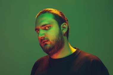 Yeşil arka planda renkli neon ışığı olan bir adamın portresi - siber punk konsepti