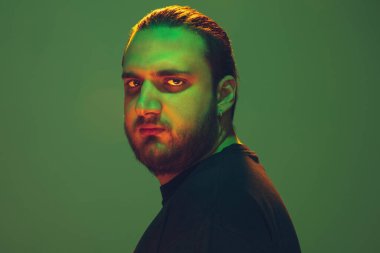 Yeşil arka planda renkli neon ışığı olan bir adamın portresi - siber punk konsepti