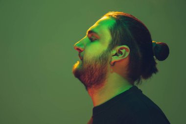 Yeşil arka planda renkli neon ışığı olan bir adamın portresi - siber punk konsepti