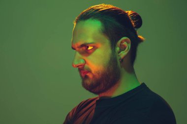 Yeşil arka planda renkli neon ışığı olan bir adamın portresi - siber punk konsepti