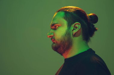 Yeşil arka planda renkli neon ışığı olan bir adamın portresi - siber punk konsepti