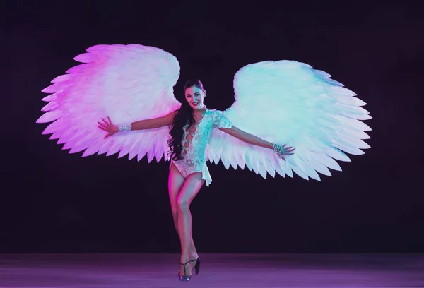 Jovem dançarina com asas de anjos em luz de néon no fundo preto — Fotografia de Stock