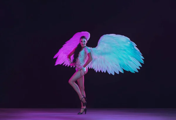 Genç bayan dansçı meleklerin kanatlarıyla siyah arka planda neon ışığı — Stok fotoğraf
