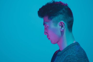 Mavi arka planda renkli neon ışığı olan bir adamın portresi - siber punk konsepti