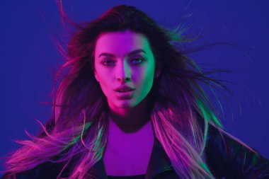 Beyaz kadın portresi mavi stüdyo arka planında neon ışıkta izole edilmiş.