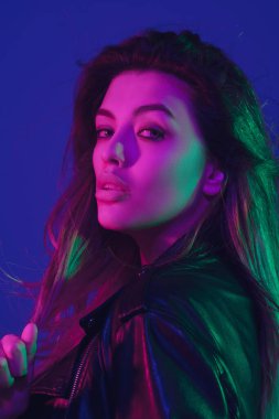 Beyaz kadın portresi mavi stüdyo arka planında neon ışıkta izole edilmiş.