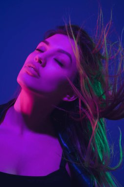 Beyaz kadın portresi mavi stüdyo arka planında neon ışıkta izole edilmiş.