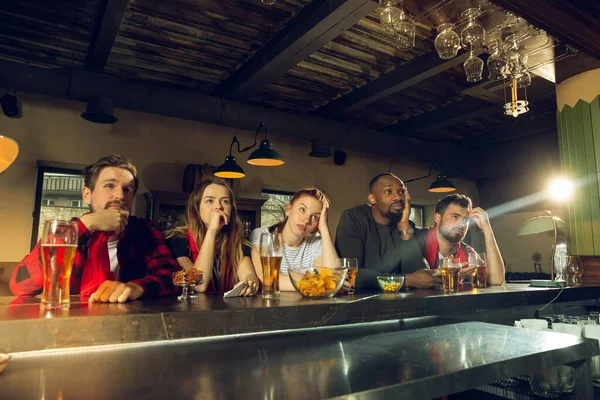 Los aficionados al deporte animando en el bar, pub y beber cerveza mientras que el campeonato, la competencia va —  Fotos de Stock