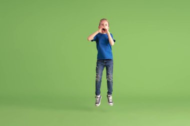 Happy boy playing and having fun on green studio background, emotions clipart