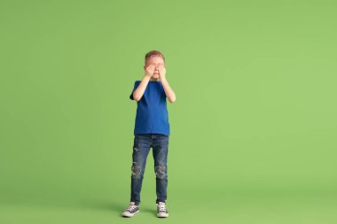 Mutlu çocuk yeşil stüdyo arka planında oynuyor ve eğleniyor, duygular