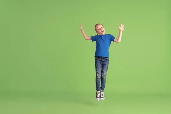 Menino feliz jogando e se divertindo no fundo do estúdio verde, emoções — Fotografia de Stock